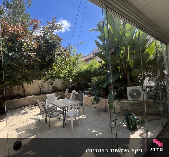 חצר עם שולחן וכיסאות, צמחייה וצינור מים